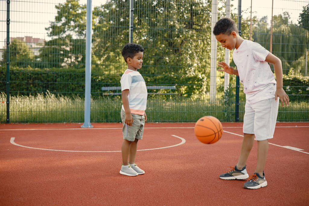 Δύο αδέλφια παίζουν μπάσκετ στο γήπεδο μπάσκετ μαζί. - Φωτογραφία, εικόνα