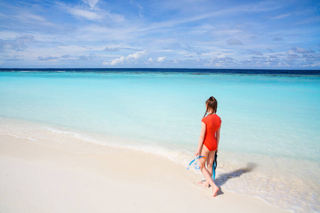 Vista posteriore della ragazza adolescente con attrezzatura per lo snorkeling in spiaggia durante le vacanze estive
 - Foto, immagini