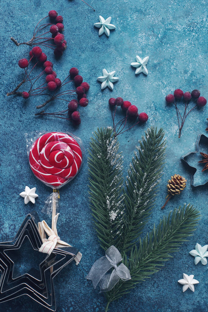 Couché plat de décoration hivernale saisonnière, arbre de Noël, bonbons, oranges séchées, baies et cônes sur table en pierre bleu foncé, fond de vacances d'hiver, vue sur le dessus  - Photo, image