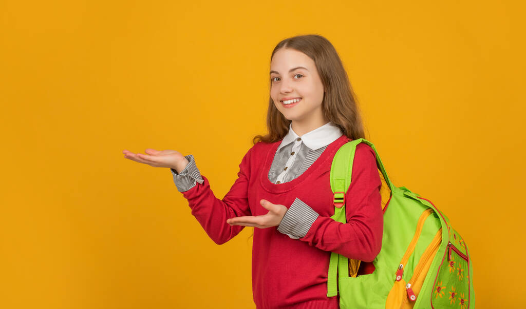 onnellinen lapsi koulun reppu esittelee tuotteen keltaisella taustalla, takaisin kouluun. - Valokuva, kuva