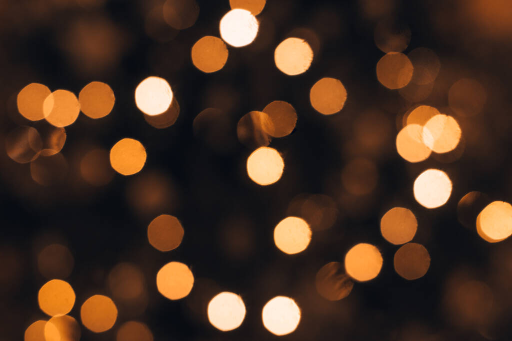Θολή φώτα ενός γιρλάντα σε ένα χριστουγεννιάτικο δέντρο σε ένα σκοτεινό φόντο.Εορταστική Χριστούγεννα και Πρωτοχρονιάτικα φόντο.Μαλακή εστίαση, αντιγραφή χώρου. - Φωτογραφία, εικόνα