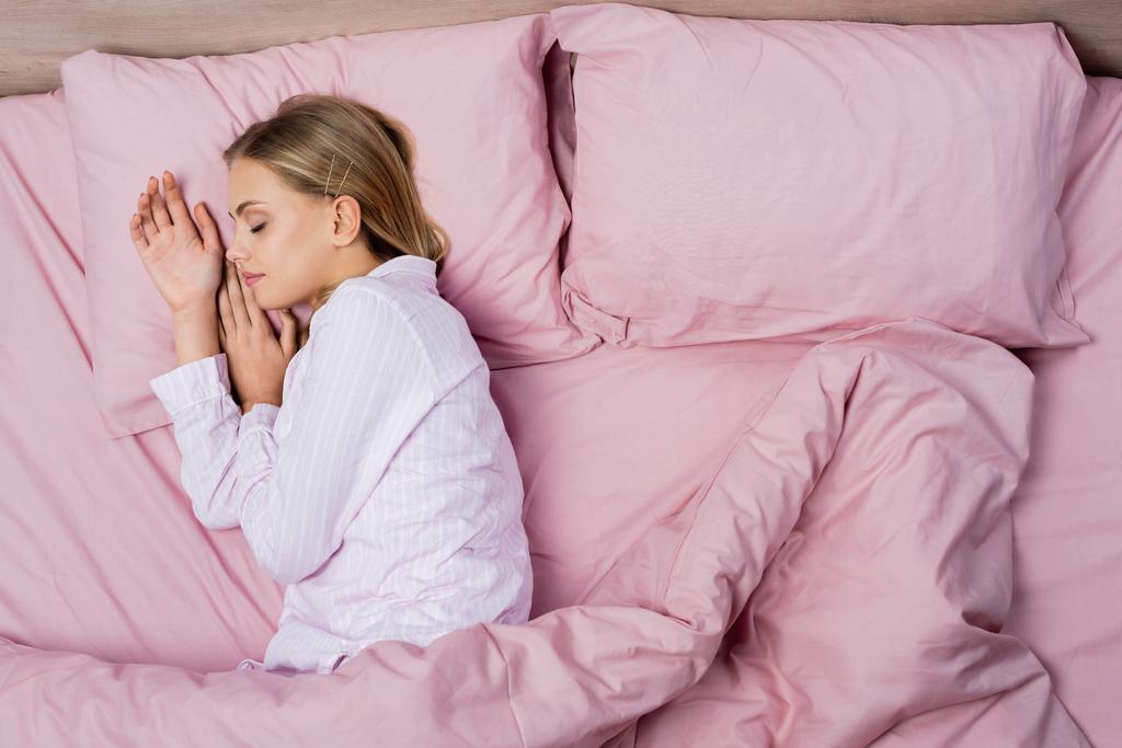 トップビューの女性でパジャマスリープオンピンク寝具上の家 - 写真・画像