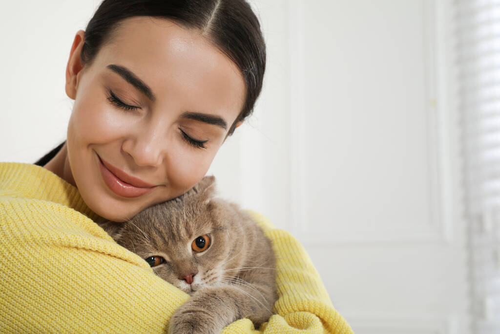 Woman with her adorable cat at home, space for text - Photo, Image