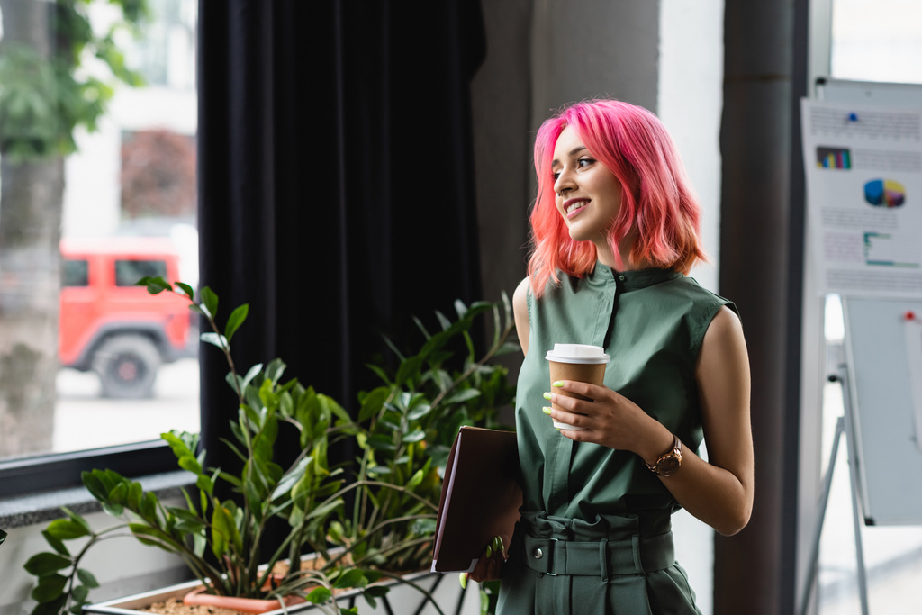 щасливий менеджер з рожевим волоссям і пірсингом тримає паперову чашку і теку
  - Фото, зображення