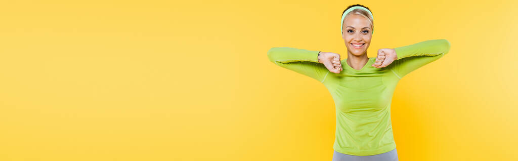 femme joyeuse et sportive souriant à la caméra tout en faisant de l'exercice sur jaune, bannière - Photo, image
