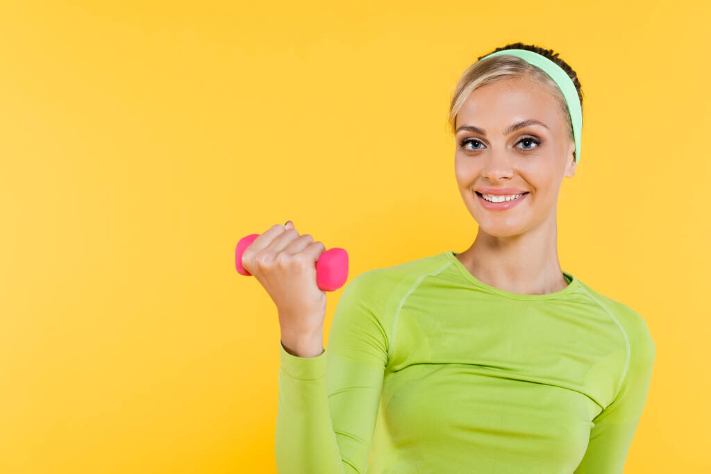 hezká žena v zeleném tričku s dlouhým rukávem trénink s činkou izolované na žluté - Fotografie, Obrázek