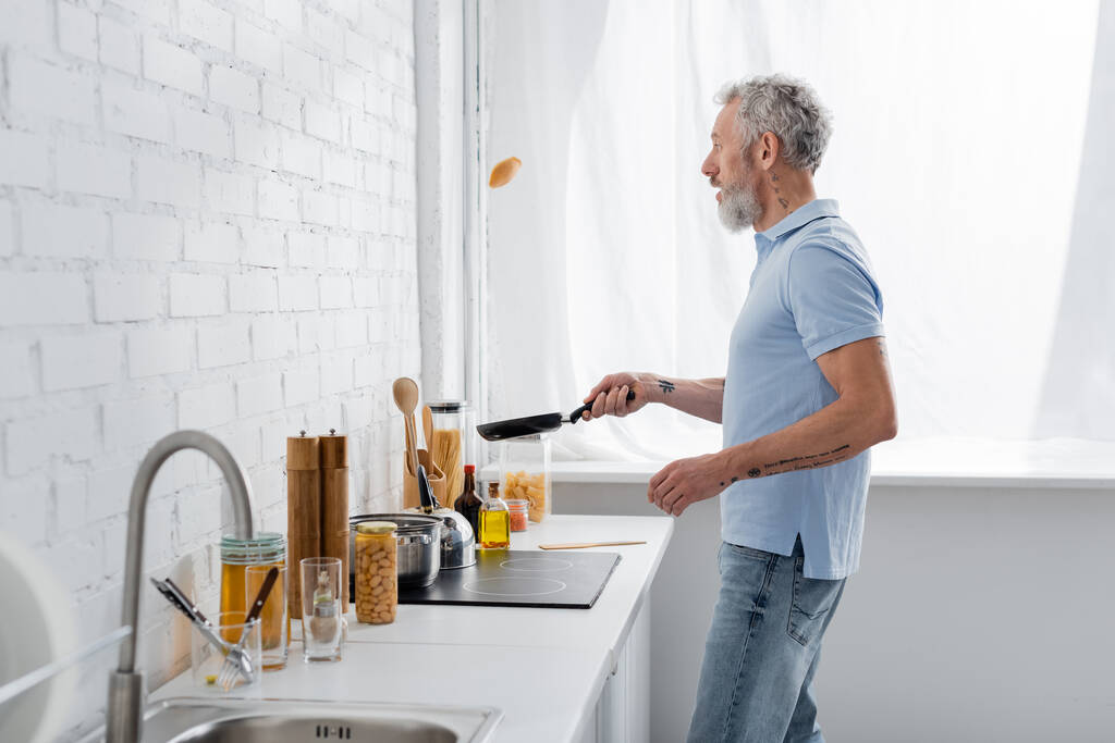 Вид збоку на дорослого чоловіка, який готує млинці на кухні. Переклад: "Ви повинні копати глибокі свердловини, якщо ви хочете очистити воду
" - Фото, зображення