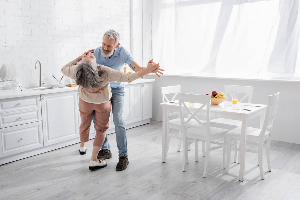 Чоловік танцює зі зрілою дружиною на кухні
  - Фото, зображення