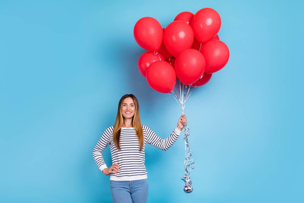 Foto de señora rubia madura optimista sostiene globos usan camisa blanca aislada sobre fondo de color azul - Foto, imagen