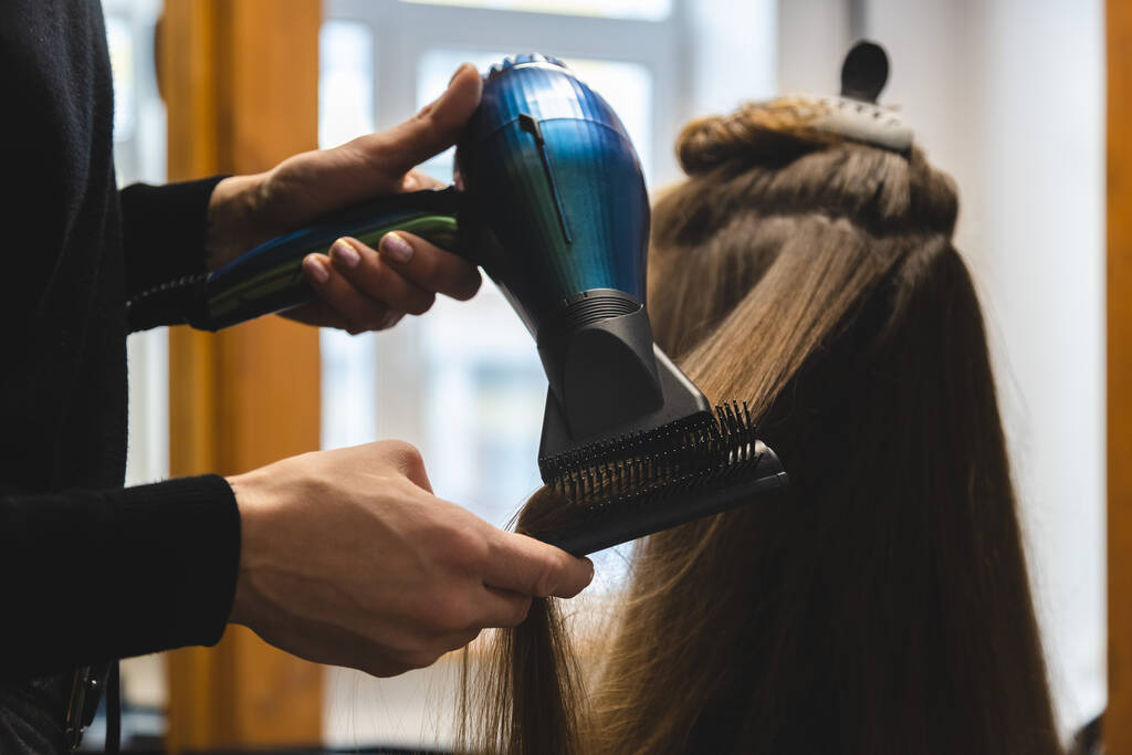 Master nainen kampaaja kuivattaa tytöt hiukset hiustenkuivaajalla ja kammat pesun jälkeen kauneushoitola - Valokuva, kuva
