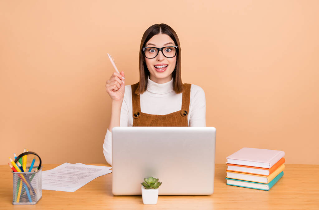 Retrato de atraente espantado inteligente alegre menina empregado usando laptop criando solução isolada sobre fundo de cor bege - Foto, Imagem