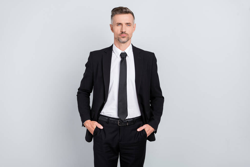 Fotografie pohledný vážný starší šéf asistent oblečený černý oblek stojící zbraně kapsy izolované šedá barva pozadí - Fotografie, Obrázek