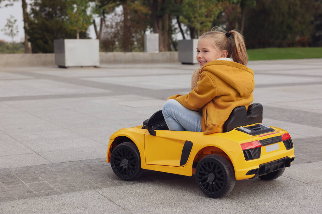 Χαριτωμένο κοριτσάκι που οδηγεί παιδικό αυτοκίνητο στην οδό Σίτυ. Χώρος για κείμενο - Φωτογραφία, εικόνα