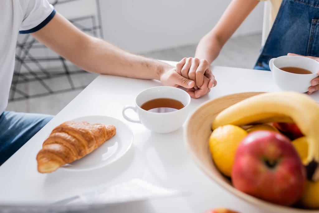 cropped view of couple holding hands during breakfast  - Photo, Image
