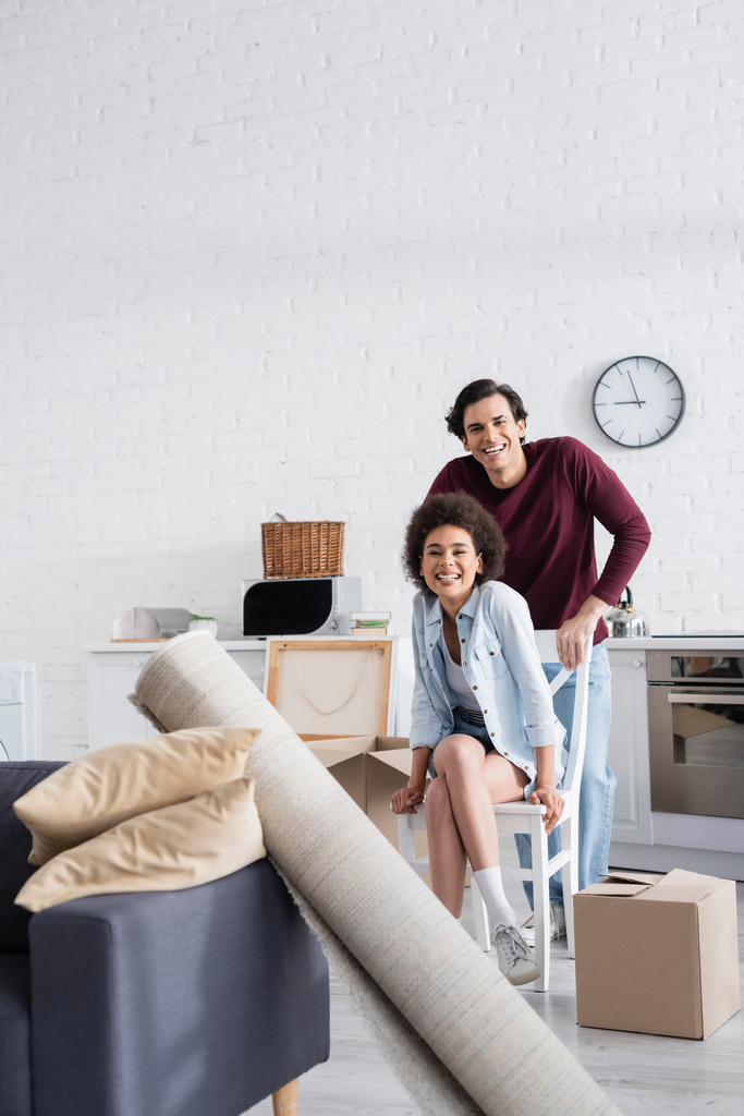 heureux couple interracial regardant caméra dans nouvelle maison - Photo, image