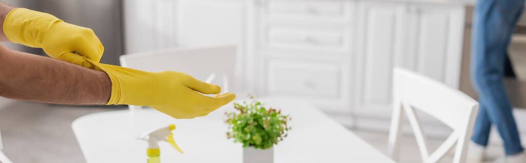 vue recadrée de l'homme portant des gants en caoutchouc jaune avec une femme floue sur le fond, bannière - Photo, image