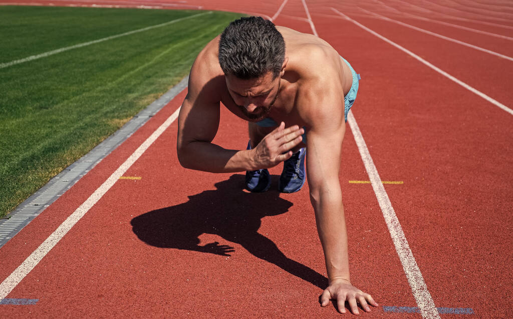 muscular guy doing push-ups standing in plank in outdoor stadium, sport - Photo, Image