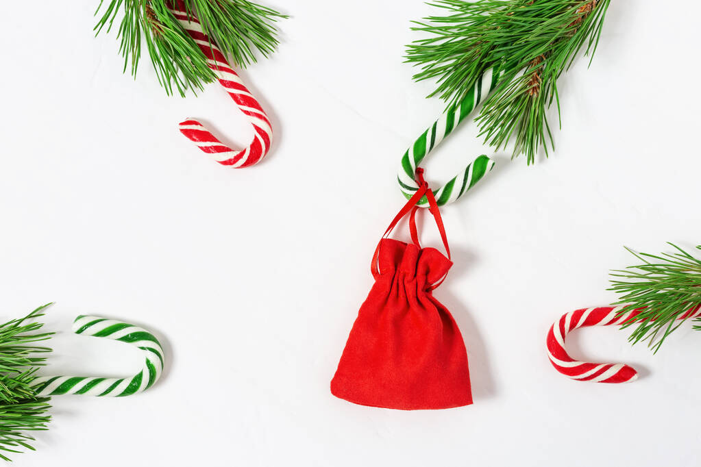 Weihnachten Hintergrund mit Zuckerstangen und Geschenk in kleinen roten Beutel. Weihnachtskomposition. Ansicht von oben, Kopierraum. - Foto, Bild
