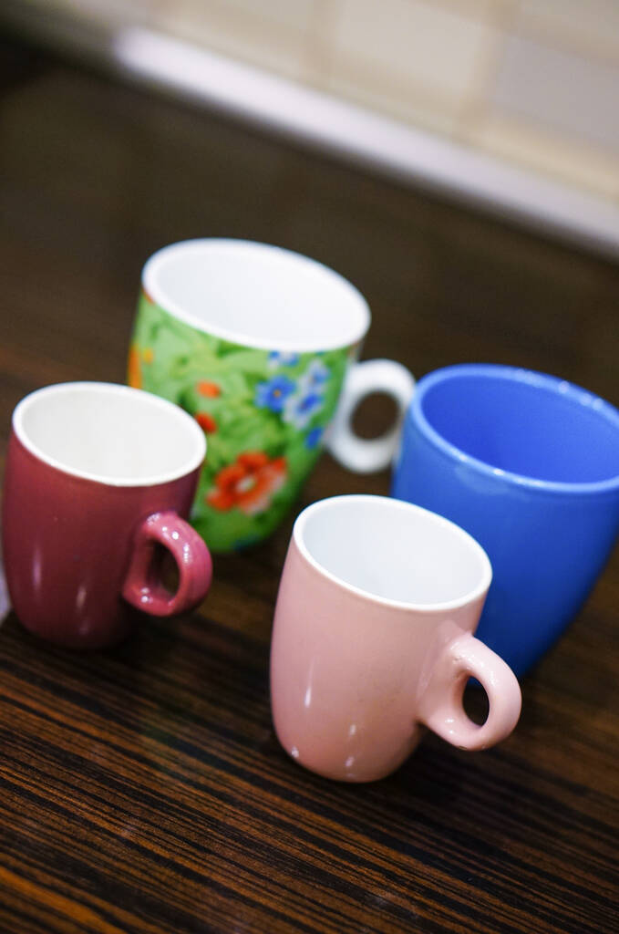 Quatre tasses à café de différentes couleurs sont sur la table de cuisine - Photo, image