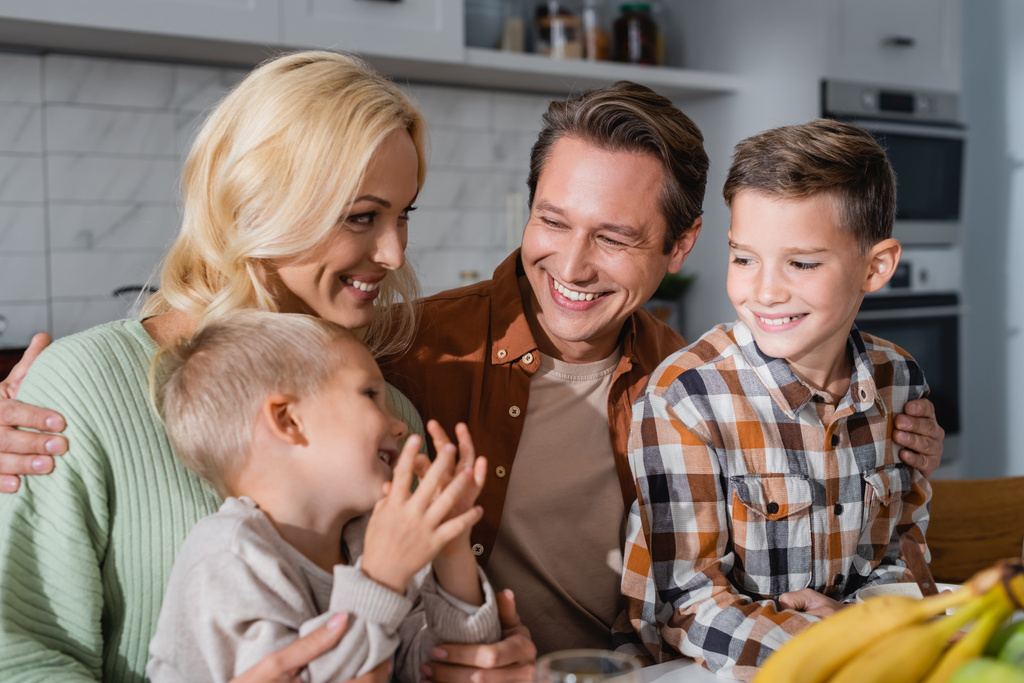радісна сім'я дивиться на маленького хлопчика біля розмитих бананів на кухні
 - Фото, зображення