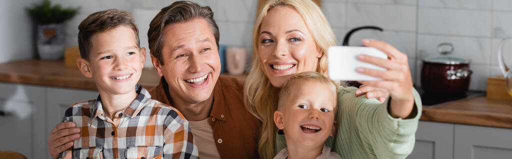 donna allegra scattare selfie su smartphone con marito e figli in cucina, banner - Foto, immagini