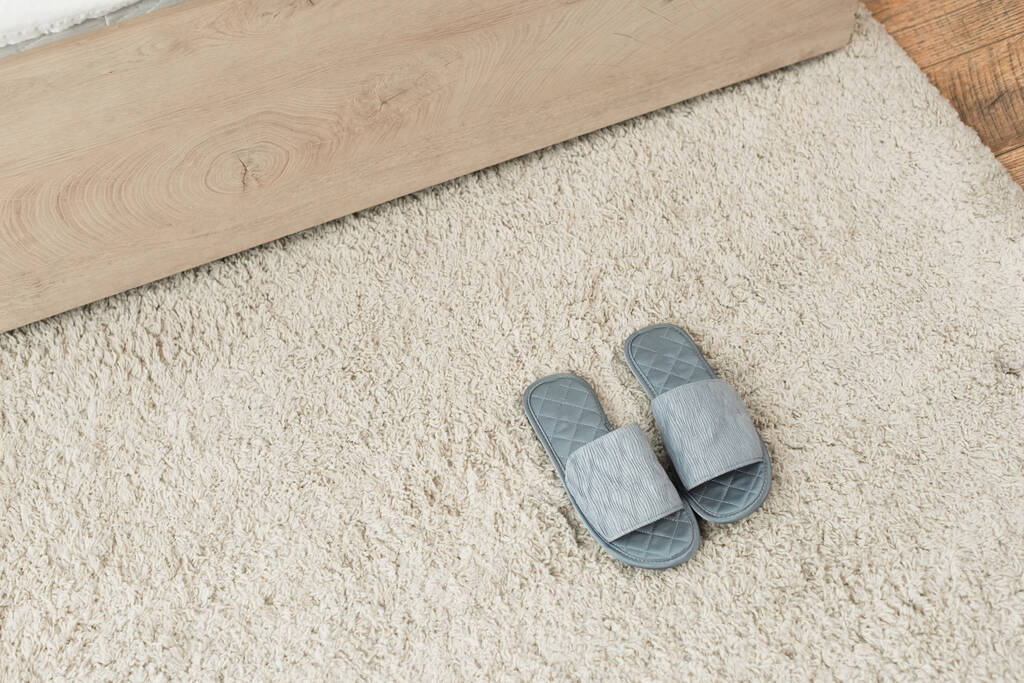 vista ad alto angolo di pantofole grigie su tappeto beige  - Foto, immagini