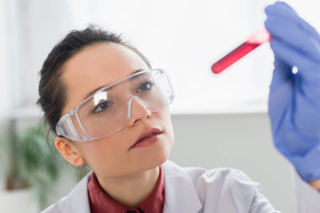 barna tudós latex kesztyű és szemüveg gazdaság kémcső vérrel - Fotó, kép