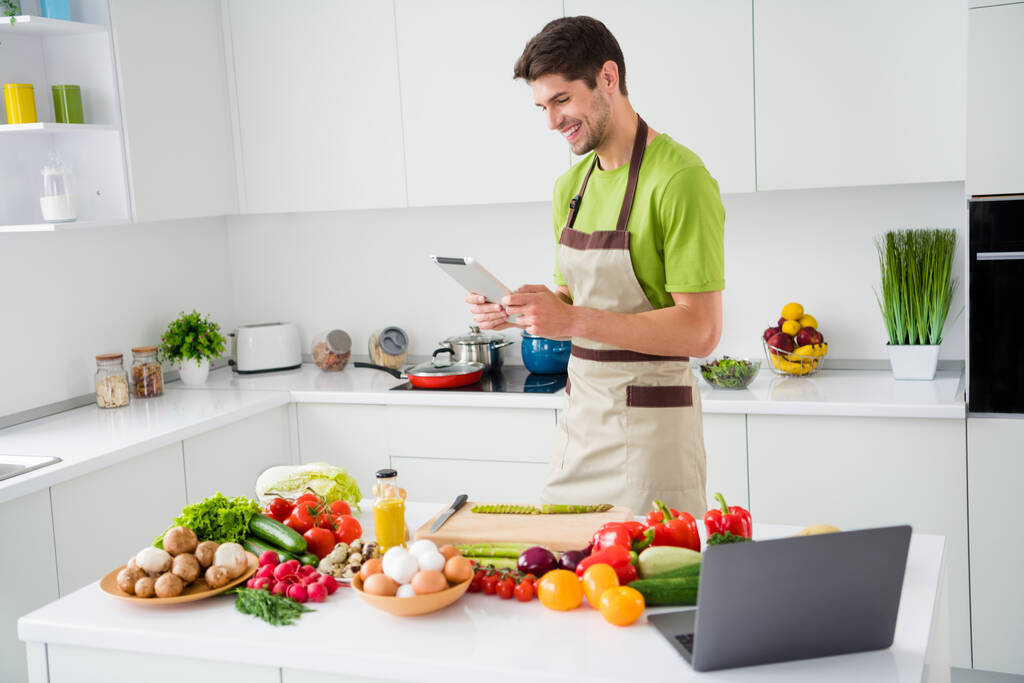 Muotokuva houkutteleva iloinen taitava kaveri ruoanlaitto herkullinen salaatti katsella video oppitunti kotona keittiö sisätiloissa - Valokuva, kuva