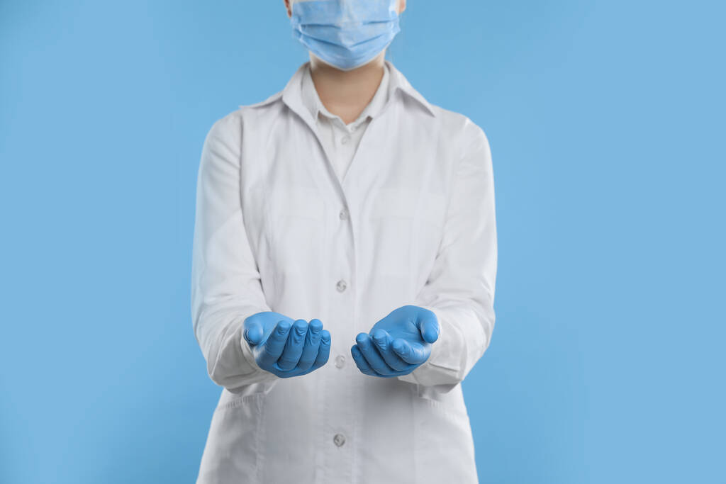 Οδοντίατρος κρατώντας κάτι σε γαλάζιο φόντο, κοντινό πλάνο - Φωτογραφία, εικόνα