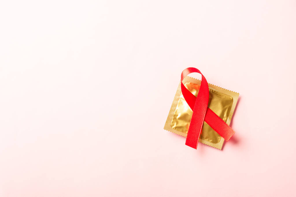 Piros íj szalag szimbólum HIV, AIDS rák tudatosság és óvszer árnyékok, stúdió lövés elszigetelt rózsaszín alapon, Egészségügyi orvostudomány szexuálisan koncepció, AIDS világnap - Fotó, kép