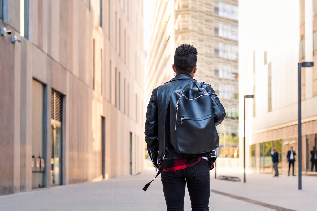 Şehirde sırt çantasıyla dolaşan şık bir genç öğrencinin arka planı, şehir yaşam tarzı kavramı. - Fotoğraf, Görsel