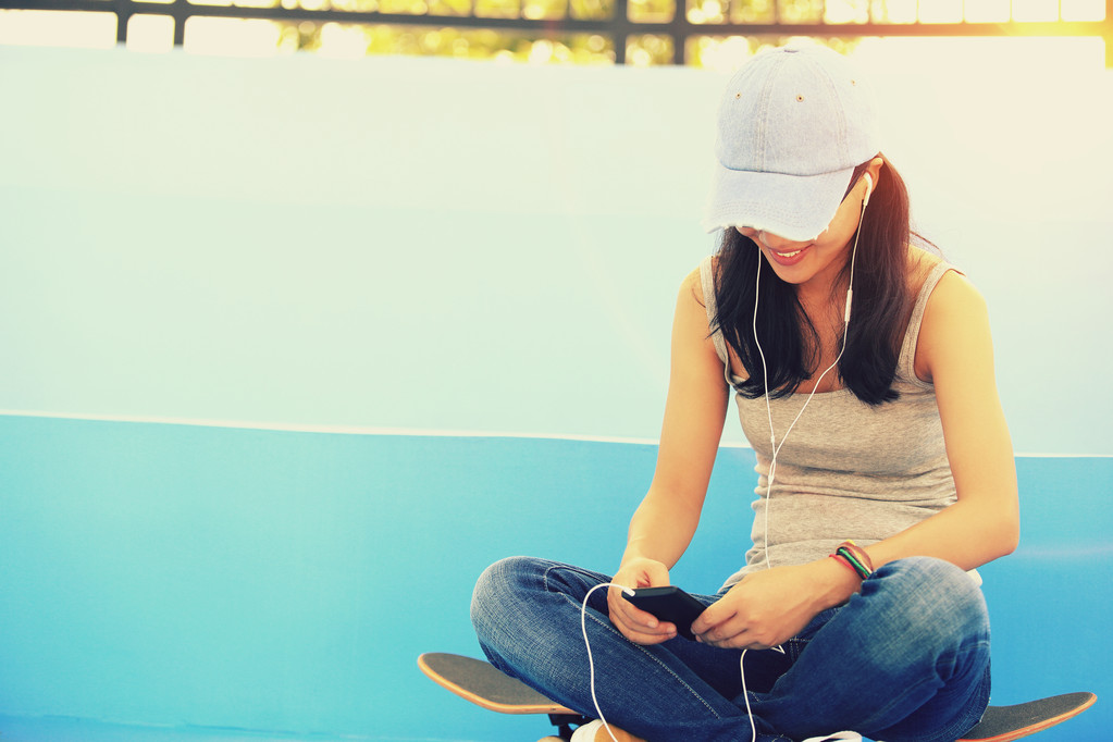 Femme skateboarder assis sur les escaliers skatepark écouter de la musique de téléphone intelligent lecteur mp3
 - Photo, image