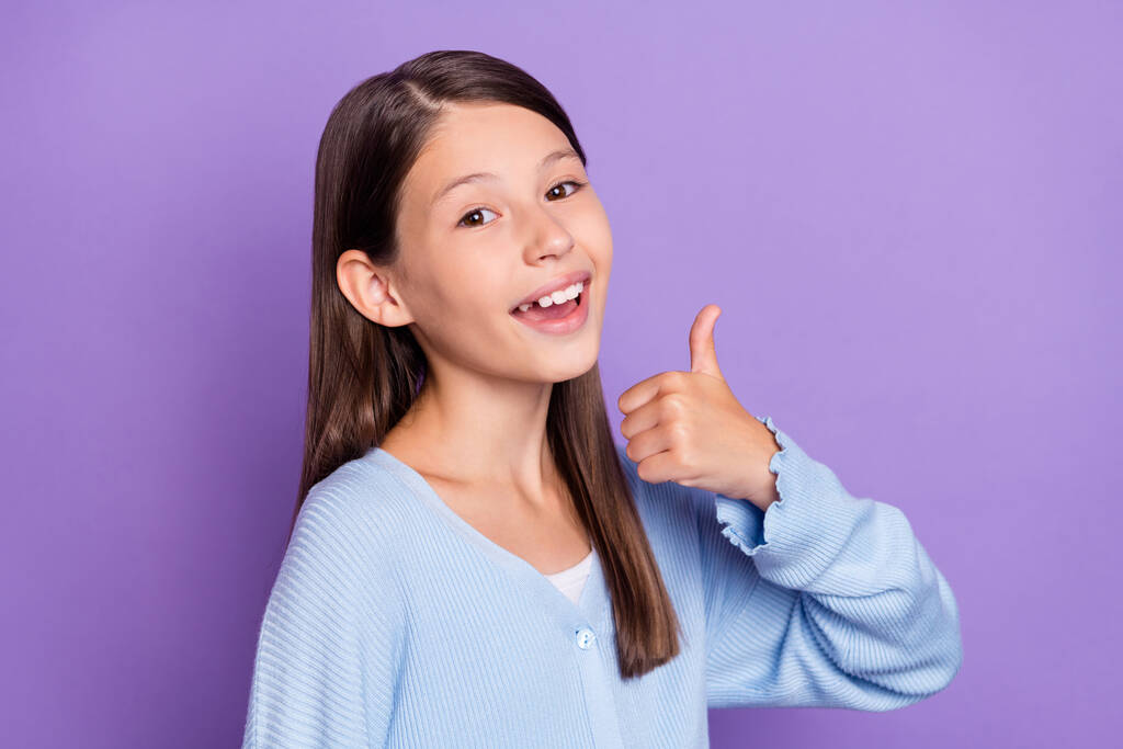 Zdjęcie pod wrażeniem brunetka mała dziewczyna pokazać kciuk do góry nosić niebieską koszulę izolowane na fioletowy kolor tła - Zdjęcie, obraz