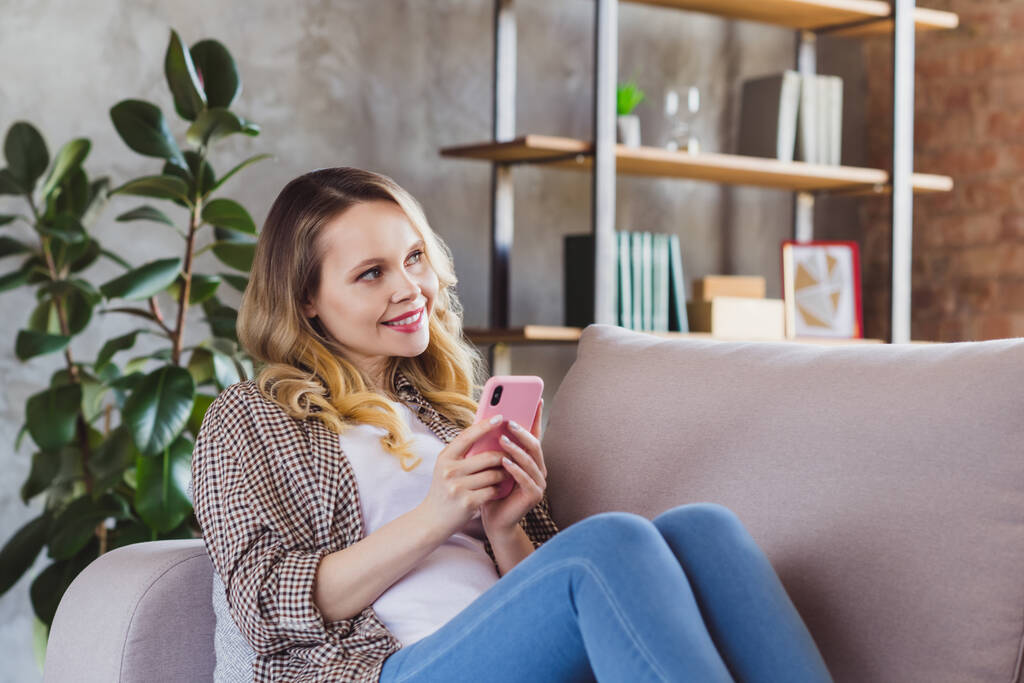 Retrato de menina alegre atraente sentado no divã gastar tempo livre usando o aplicativo gadget 5g no interior estilo industrial dentro de casa - Foto, Imagem
