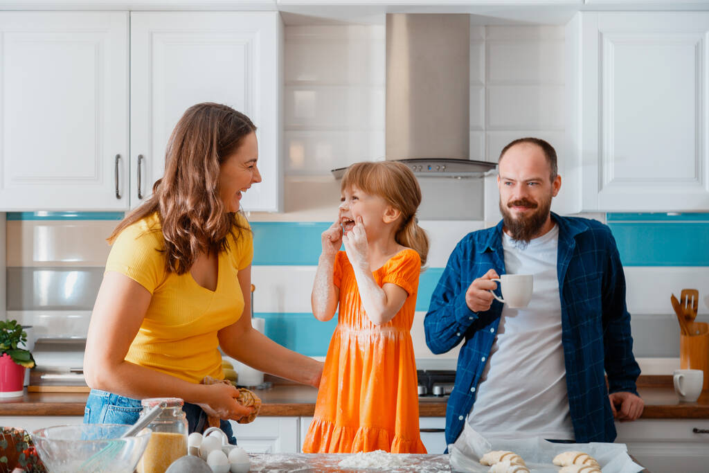 Happy rodinné pečení pečení pečivo croissanty společně v kuchyni interiér matka otec a dcera Bavte se a zašpinit moukou doma. Šťastní usměvaví rodiče si o víkendu připravují jídlo - Fotografie, Obrázek