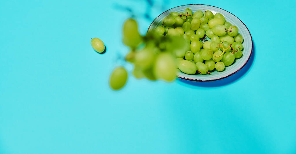 a bunch of appetizing white table grapes on an oblique blue and grey background - 写真・画像