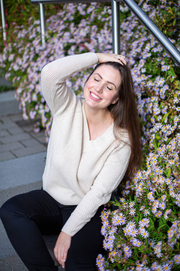 witte europese vrouw in trui in de buurt van bloemen met gesloten ogen - Foto, afbeelding