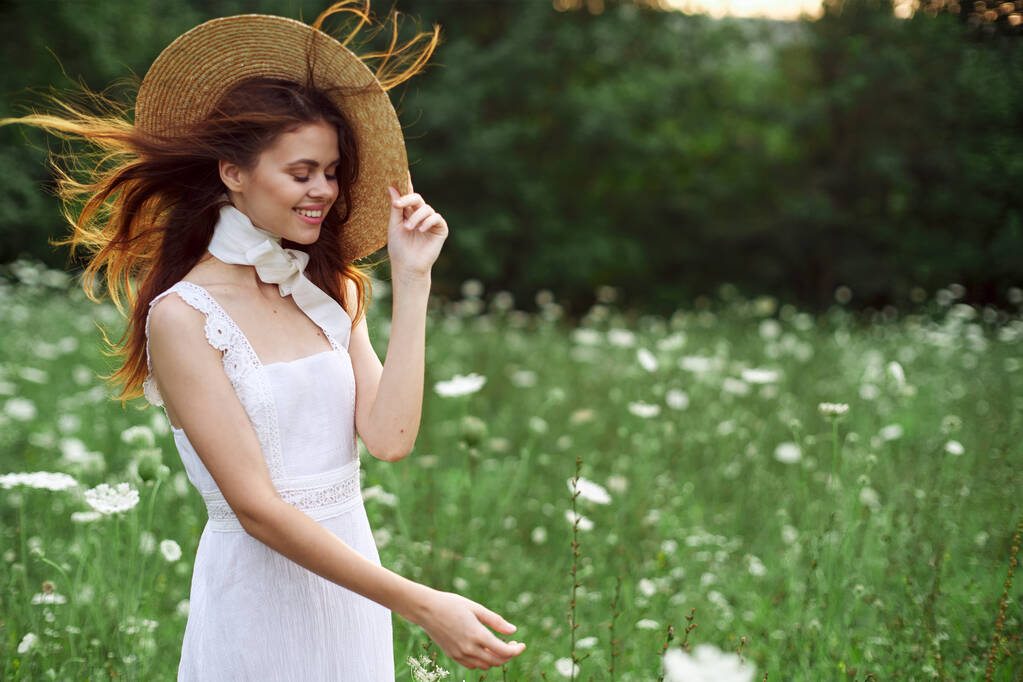 hermosa mujer en un sombrero en un campo con flores caminar - Foto, Imagen