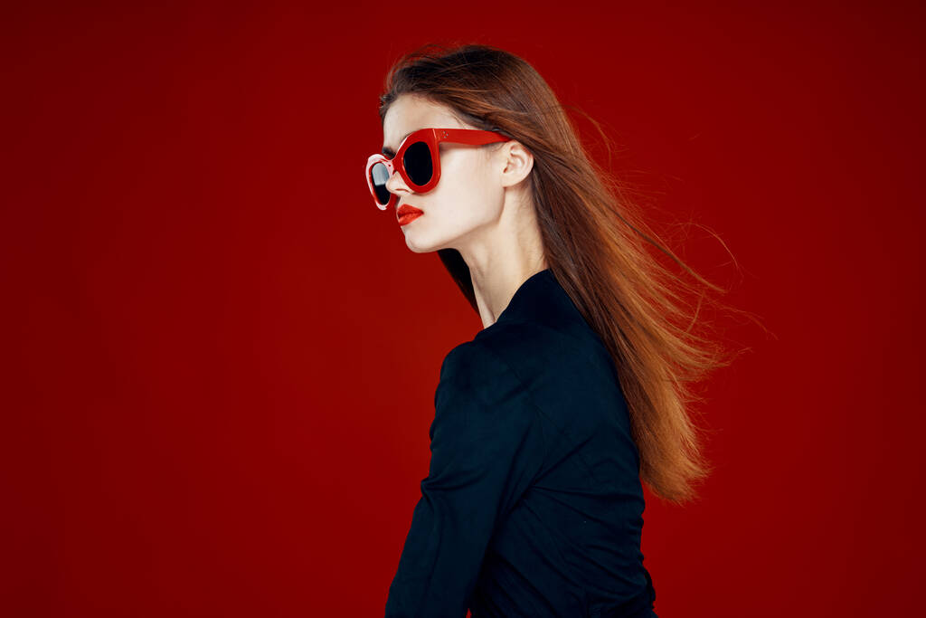 mulher bonita usando óculos de sol moda posando penteado fundo vermelho - Foto, Imagem