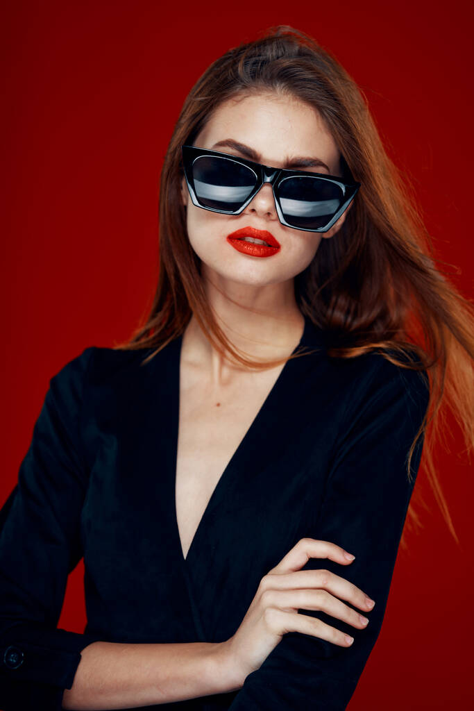 vidám divatos nő visel napszemüveg piros ajkak pózol piros háttér - Fotó, kép