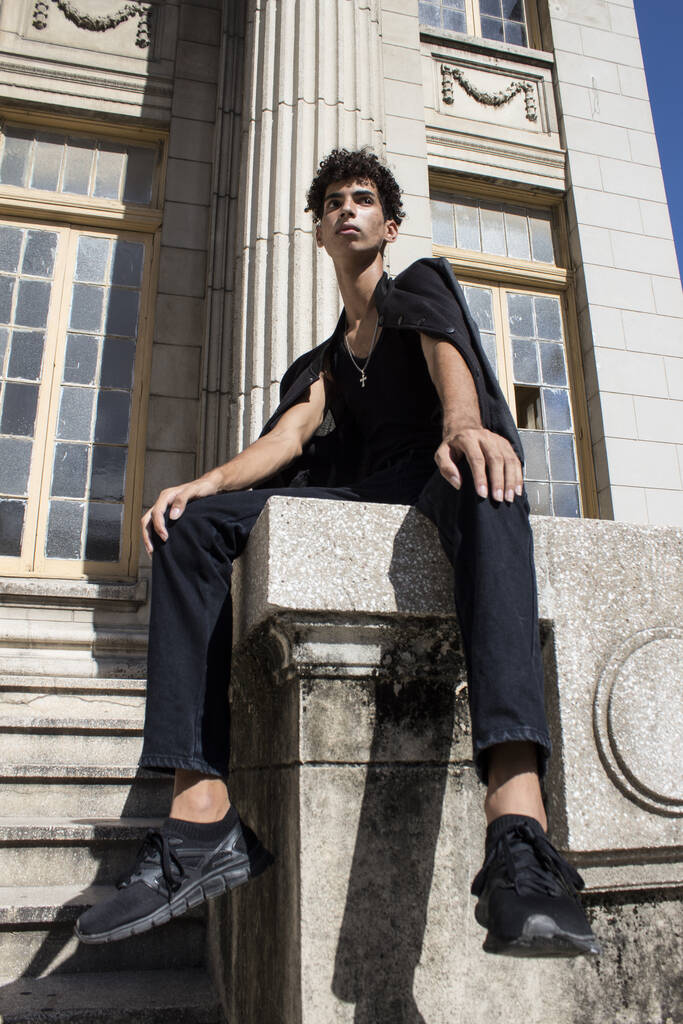 A young Hispanic male in a black outfit posing on the streets on a sunny day in Old Havana, Cuba - Foto, imagen