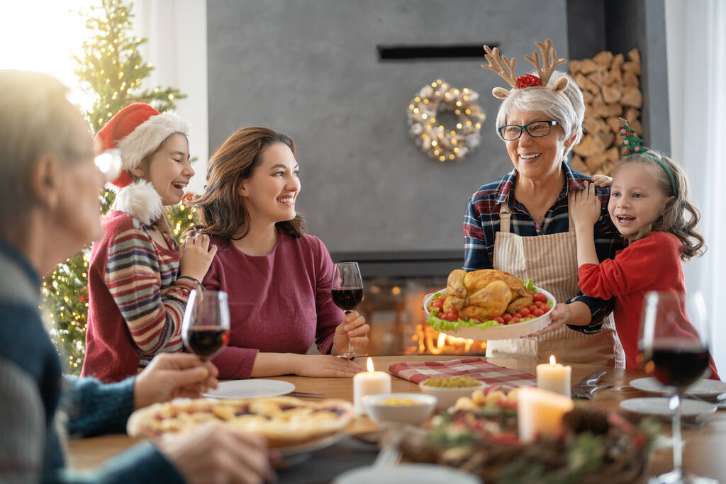 メリークリスマス幸せな家族は家で夕食を食べている。ツリーの近くでお祝いの休日と団結. - 写真・画像