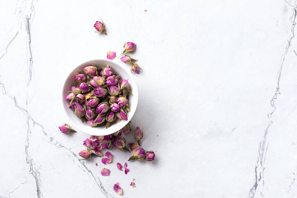 Top view of bowl with dried rose buds for fragrant tea on white marble background with copy space - Photo, Image