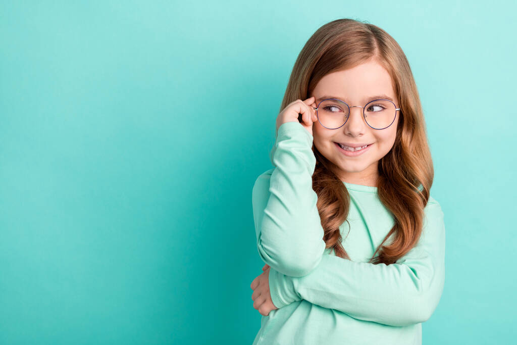 Фото молодой девушки счастливой позитивной улыбкой руки касаются очки заинтересованы взгляд пустое пространство изолированы на бирюзовом фоне цвета. - Фото, изображение