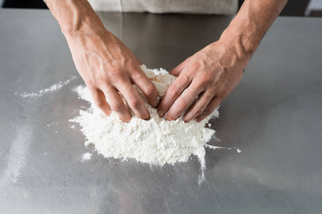 Обрізаний вид шеф-кухаря, який робить тісто на кухонному столі
  - Фото, зображення
