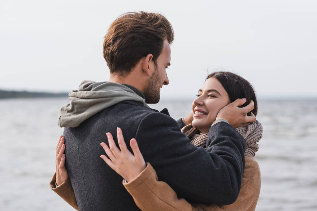 happy young couple embracing near sea during autumn walk - Photo, Image