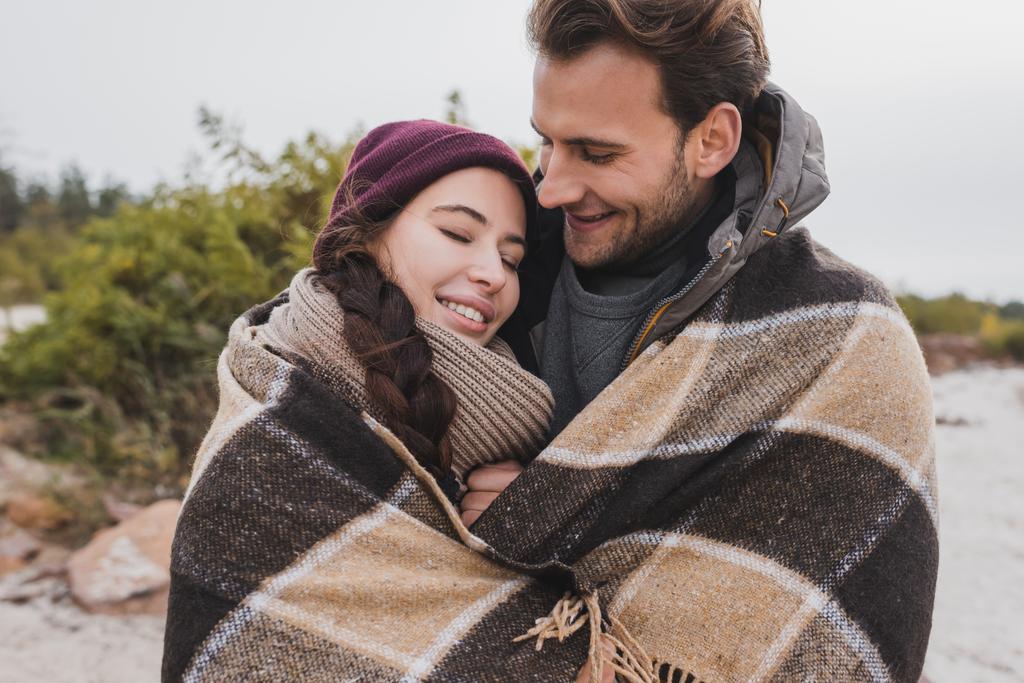 幸せな若いカップル暖かいですチェッカー毛布屋外で - 写真・画像