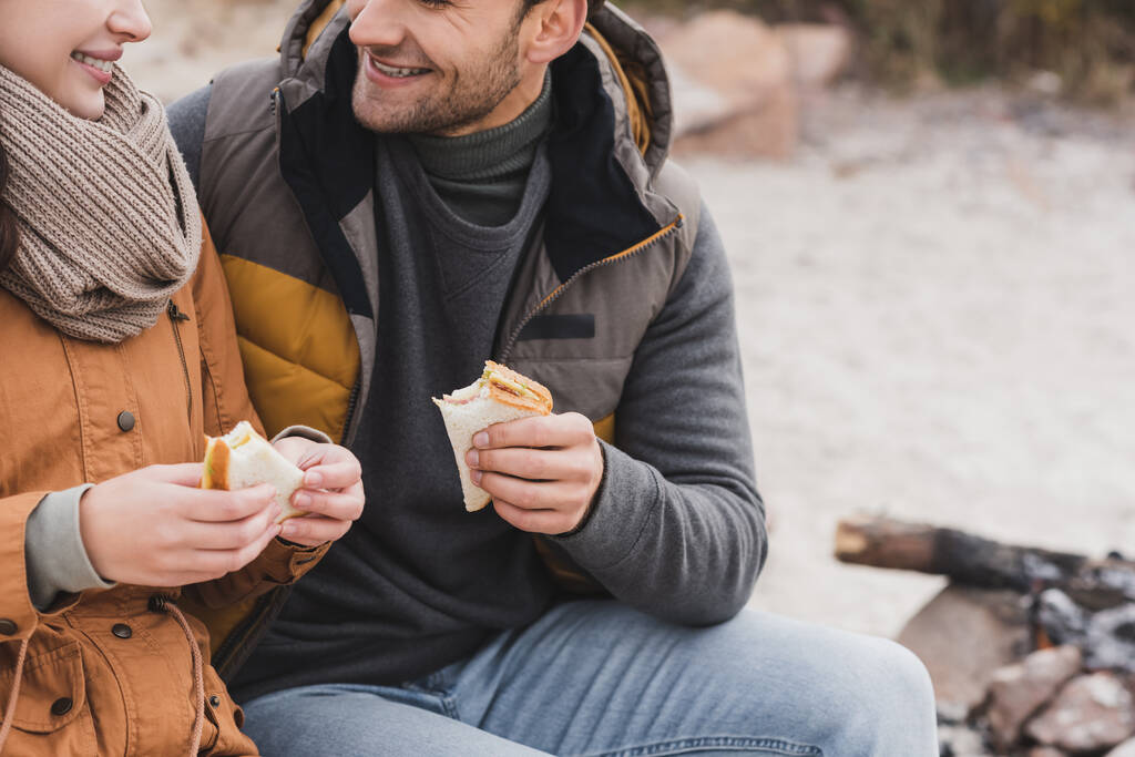 vista cortada de casal segurando sanduíches durante parada ao ar livre - Foto, Imagem