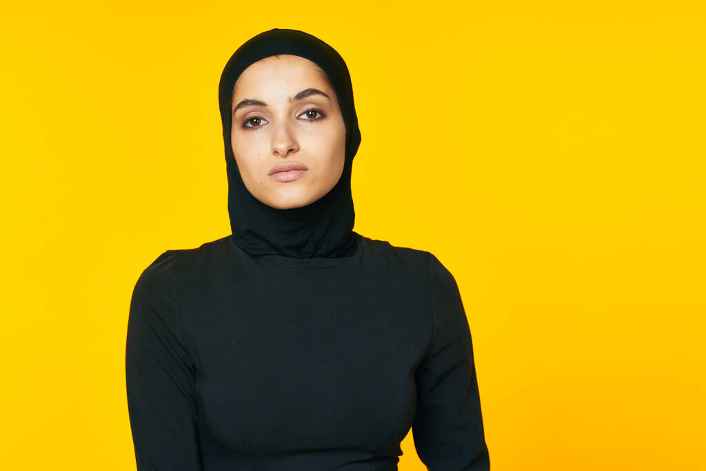 イスラム教の黄色の背景をしたイスラム教徒の服を着た女性 - 写真・画像