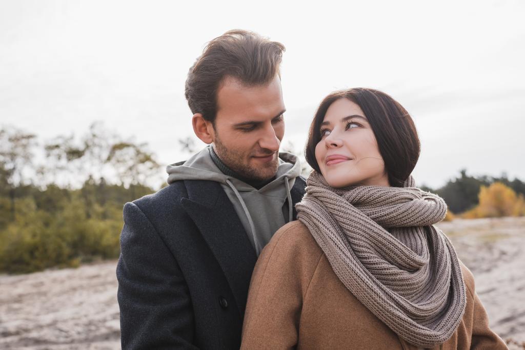 positive couple in autumn outfit looking at each other outdoors - Photo, Image